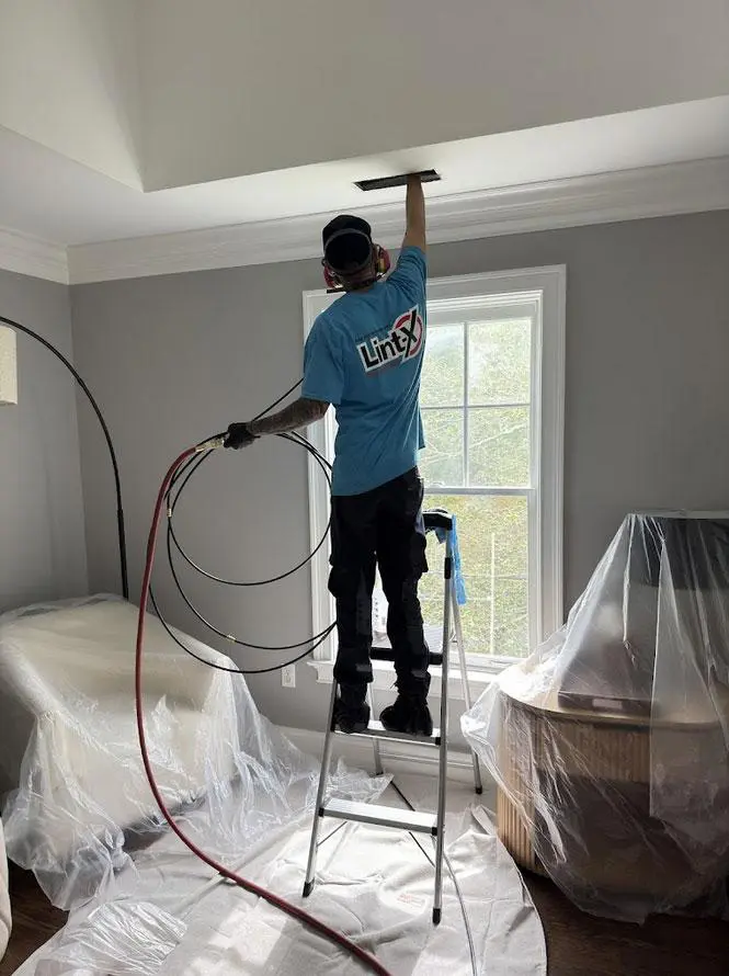 Technician performing air duct cleaning with vacuum hose at register and sealed vents